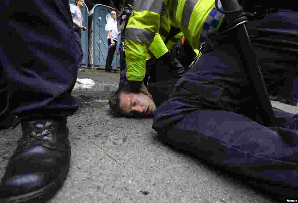 Police detain an anti-fracking demonstrator outside a drill site run by Cuadrilla Resources, near Balcombe in southern England. 