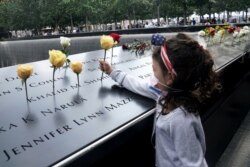 Una niña coloca una flor en el monumento a las víctimas de los ataques del 11 de septiembre de 2001 en Nueva York.