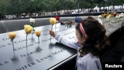 A girl places a flower on the edge of the North pool during ceremonies on the 19th anniversary of the September 11, 2001 attacks on the World Trade Center at the 911 Memorial in the Manhattan borough of New York City, New York, U.S., September 11, 2020…