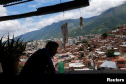 FILE - Victor Cordova looks outside of his house at Petare slum in Caracas, Venezuela, Aug. 21, 2017.