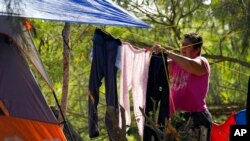 FILE - A person seeking asylum in the U.S. hangs laundry on a clothesline at a camp in Matamoros, Mexico, Nov. 19, 2020. Mexican authorities are working to close the improvised camp along the Rio Grande that has housed thousands of asylum-seekers.
