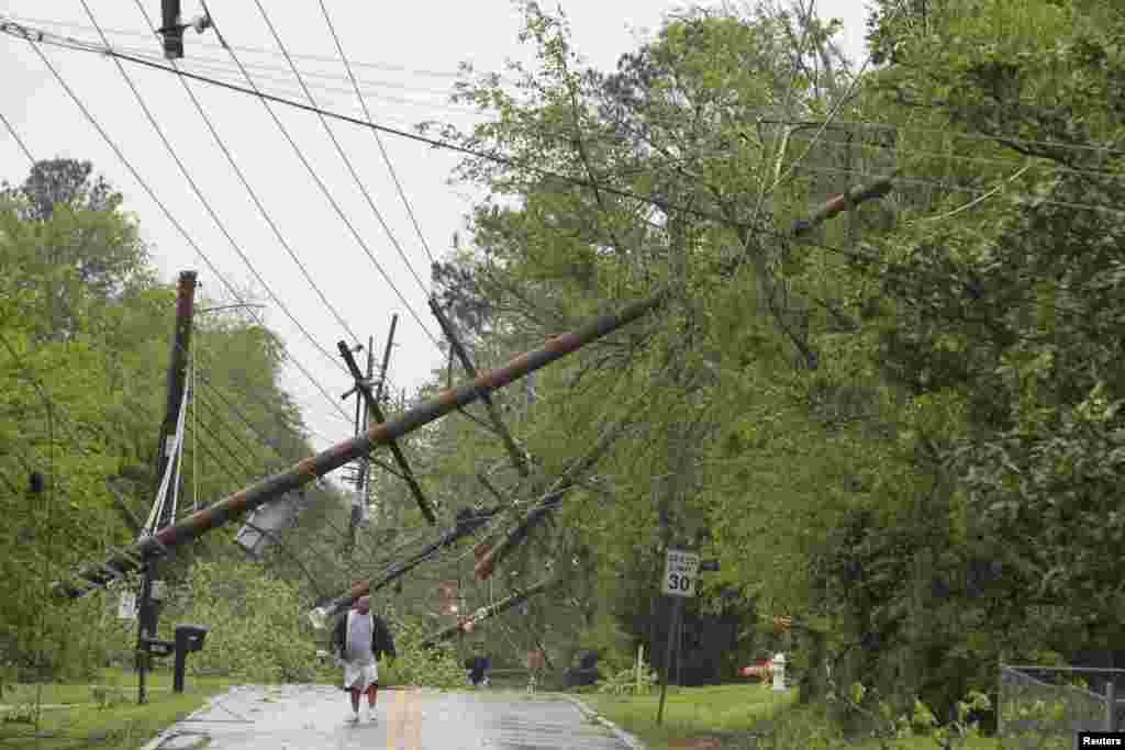 A resident makes his way down Jackson Street and away from the tornado damaged area in Tupelo, Mississippi. On a second day of ferocious storms that have claimed at least 19 lives in the southern United States, a tornado tore through the Mississippi town of Tupelo causing widespread destruction to homes and businesses, according to witnesses and local emergency officials.