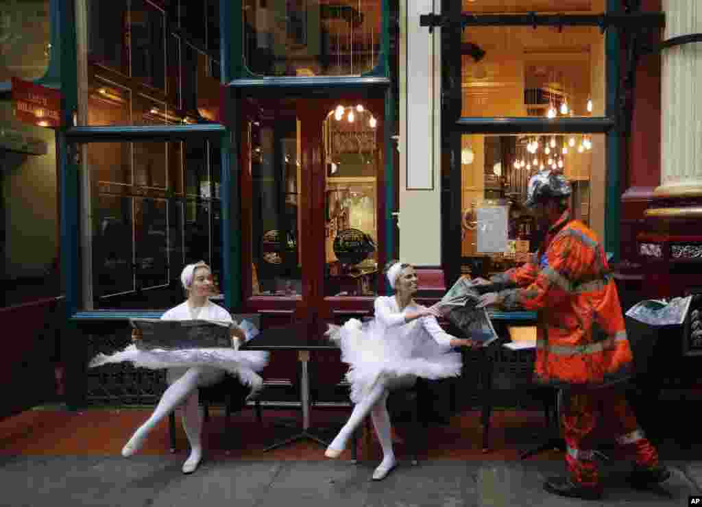 Actors sit in the streets of Leadenhall Market in London. A Large-scale artwork was unveiled accompanied by characters to tell the story of London&#39;s world-famous insurance market in a three day-campaign that aims to explain how insurers and brokers support people, businesses, charities and governments all round the world.