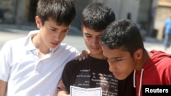 Boys read a leaflet dropped by the Syrian army over opposition-held Aleppo districts asking residents to cooperate with the military and calling on fighters to surrender, July 28, 2016. 