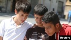 FILE - Boys read a leaflet dropped by the Syrian army over opposition-held Aleppo districts asking residents to cooperate with the military and calling on fighters to surrender, July 28, 2016.