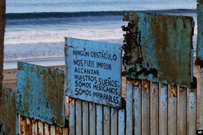 A sign that reads in Spanish "No obstacle can stop us from our dreams. We are Mexicans. We are unstoppable," hangs on border structure from the Mexican side where the border meets the Pacific Ocean, Nov. 16, 2018.