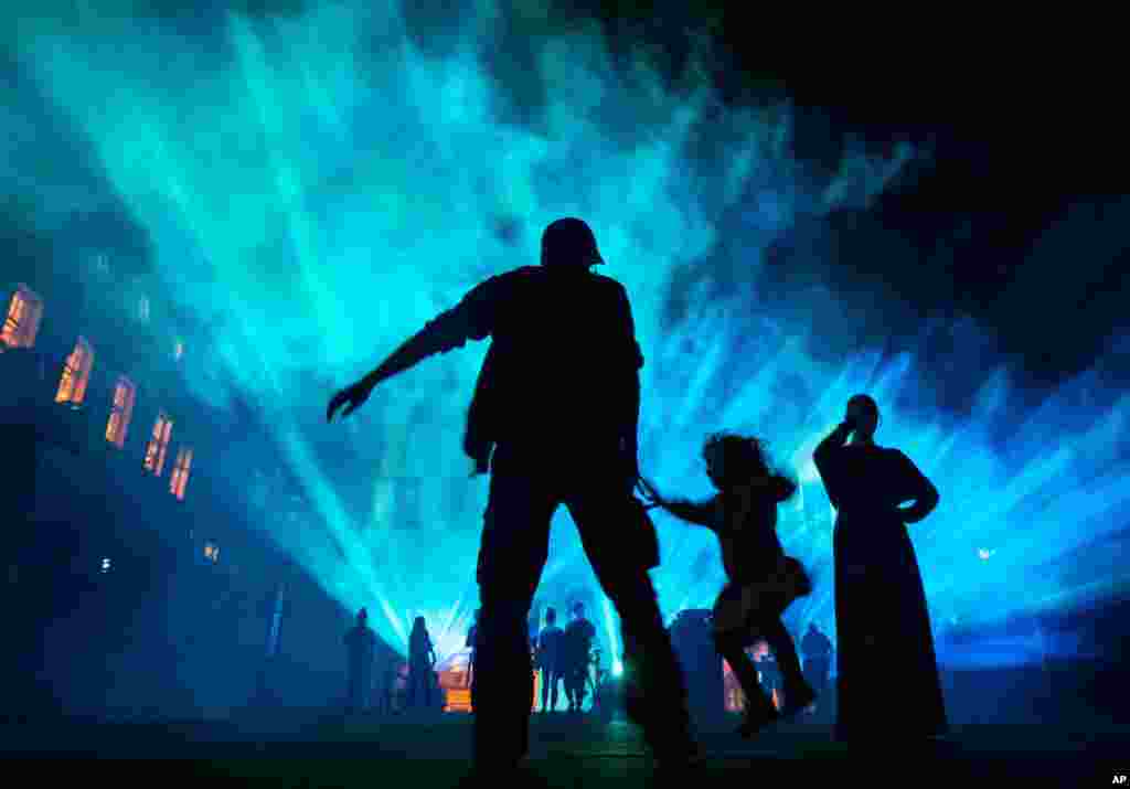 Visitors stand in front of a facade projection during the Genius Loci festival in Weimar, Germany, Aug. 11, 2019.