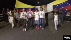 Luz Adriana Chalarca, in white shoes and carrying a figure of the Christ child, leads a prayer vigil on a bridge linking Cúcuta, Colombia, and northwest Venezuela. (C. Mendoza/VOA Spanish Service)