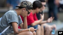 A youth checks his cell phone in Sao Paulo, Brazil, Dec. 17, 2015. 