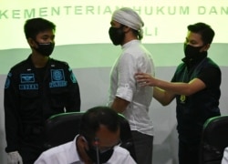 Instruktur yoga Wissam Barakeh (tengah) dari Suriah ditangkap oleh petugas Imigrasi sebelum konferensi pers di Rumah Detensi Imigrasi di Jimbaran, Bali, 24 Juni 2020. (Foto: dok).