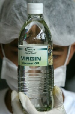 Seorang pekerja Filipina memeriksa minyak Kelapa Murni dalam kemasan baru di sebuah perkebunan di Provinsi Quezon, selatan Manila, sebelum dikirim ke supermarket dalam gambar ini, 11 Agustus 2004. (Foto: Reuters)