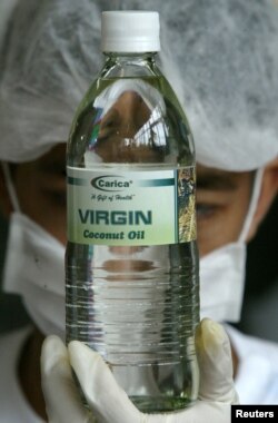 Seorang pekerja Filipina memeriksa minyak Kelapa Murni dalam kemasan baru di sebuah perkebunan di Provinsi Quezon, selatan Manila, sebelum dikirim ke supermarket dalam gambar ini, 11 Agustus 2004. (Foto: Reuters)