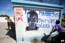 FILE - A demonstrator spray paints the message in Creole "We demand justice for all cholera victims" outside United Nations headquarters to protest the U.N. peacekeeping mission in Port-au-Prince, Haiti, Oct. 15, 2015.