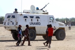 Sudanese children walk past an armored vehicle of the United Nations and African Union peacekeeping mission (UNAMID) in Kalma Camp for internally displaced people in Nyala, the capital of South Darfur, Dec. 30, 2020.