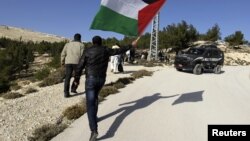 A Palestinian protester holds a flag as he arrives at an area known as 'E1', which connects the two parts of the Israeli-occupied West Bank outside Arab suburbs of East Jerusalem, January 15, 2013.