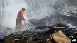 A firefighter puts out a fire on a pile debris left behind after flood waters, one of Thailand's worst floods in five decades, receded in Bangkok, January 6, 2012.