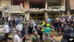 People gather near a damaged building at the scene of an Israeli missile strike in the southern suburbs of Beirut, Sept. 20, 2024.