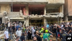 Orang-orang berkumpul di dekat gedung yang rusak akibat serangan rudal di kawasan permukiman di selatan Beirut, Jumat, 20 September 2024. (Foto: Bilal Hussein/AP Photo)