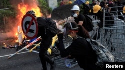 An anti-government protester shelters with a traffic sign during a demonstration in Sha Tin district, on China's National Day in Hong Kong, China October 1, 2019.