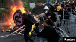 Seorang pemrotes anti-pemerintah berlindung dengan rambu lalu lintas saat berlangsungnya aksi demo di distrik Sha Tin, pada Hari Nasional China di Hong Kong, China 1 Oktober 2019.