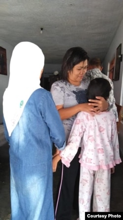 Dwi Wulandari memeluk salah seorang putrinya. (Courtesy: Migrant Care)
