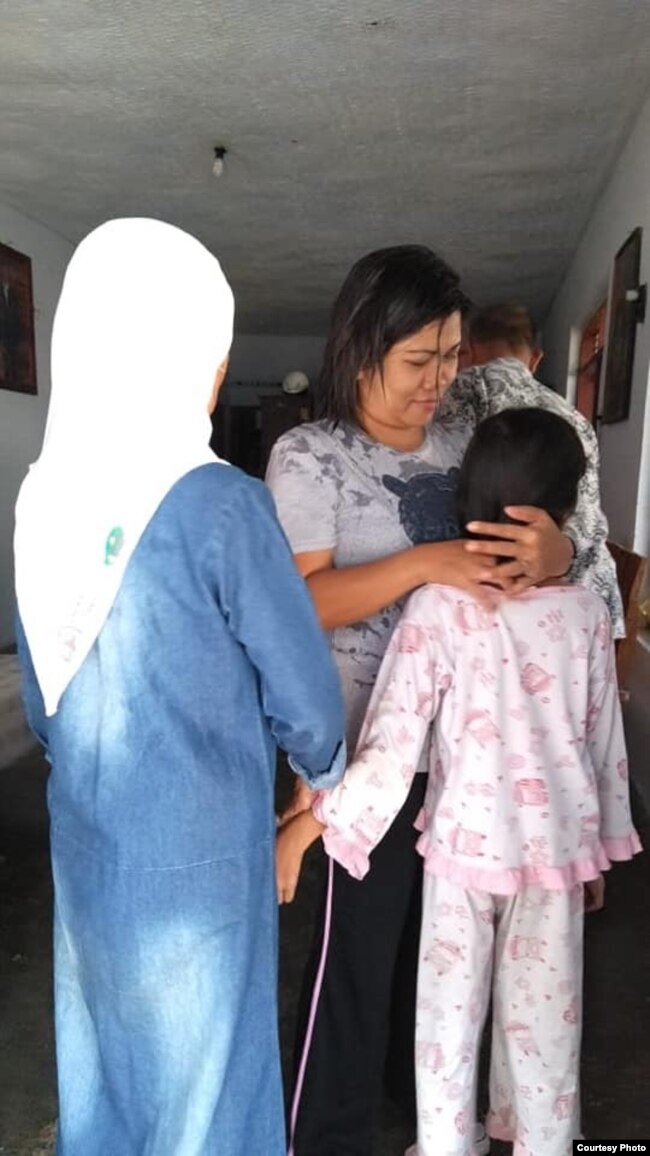 Dwi Wulandari memeluk salah seorang putrinya. (Courtesy: Migrant Care)