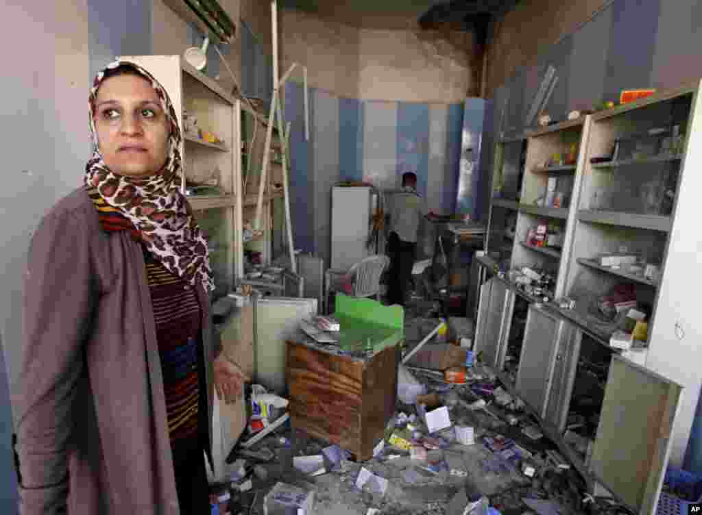 People inspect damages of a car bomb attack in the Sha'ab neighborhood of Baghdad, August 28, 2013.