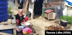 Nurjanah, 29, mencuci pakaian di luar tenda sambil memasak air minum untuk kebutuhan keluarganya, Selasa, 18 Juni 2019. (Foto:Yoanes Litha/VOA)