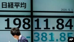 A man walks past an electronic stock board showing Japan's Nikkei 225 index at a securities firm in Tokyo on May 1, 2020. 