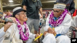 Kathleen Chavez (kiri) berbincang dengan ayahnya Ray Chavez, yang berusia 104 tahun, salah satu penyintas paling tua dari serangan Pearl Harbor, dalam peringatan peristiwa itu di Honolulu (7/12). (AP/Eugene Tanner)