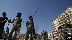 Military personnel stand next to dismantled tents at Tahrir Square in Cairo, August 1, 2011