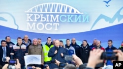 Russian President Vladimir Putin, center, speaks to workers after riding a train across a bridge linking Russia and the Crimean peninsula in Taman, Russia, Dec. 23, 2019.
