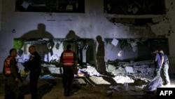 Members of Israel's Home Front Command and police forces inspect a crater left by an exploded projectile at a heavily damaged school building in Israel's southern city of Gedera on October 1, 2024.