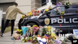 In this March 23, 2021, photo, a man leaves a bouquet on a police cruiser parked outside the Boulder Police Department after an officer was one of the victims of a mass shooting at a King Soopers grocery store in Boulder, Colorado. (AP)