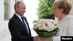 Russian President Vladimir Putin welcomes German Chancellor Angela Merkel during their meeting in the Black Sea resort of Sochi, Russia, May 18, 2018. 