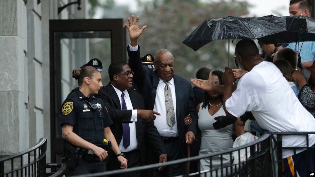 Bill Cosby, center, gestures while exiting the Montgomery County Courthouse with his publicist Andrew Wyatt, second from left, after a mistrial was declared in his sexual assault trial, June 17, 2017. 