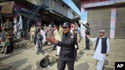 Policemen ask residents to disperse as they stand near the site of a deadly suicide bomb attack at a paramilitary training center in Mardan, northwest Pakistan, February 10, 2011.