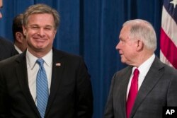 FBI Director Christopher Wray, left, smiles with Attorney General Jeff Sessions before a news conference about the arrest of Cesar Sayoc, 56, in the package bomb case, at the Department of Justice, Oct. 26, 2018, in Washington.
