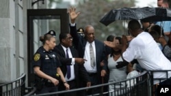 Bill Cosby, tengah, melambaikan tangan saat keluar dari Gedung Pengadilan Montgomery County, bersama agennya Andrew Wyatt, kedua dari kiri setelah batal sidang dinyatakan dalam pengadilan penyerangan seksual di Norristown, Pa, Sabtu, 17 Juni 2017 (foto: AP Photo/Matt Slocum)