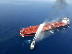 An Iranian navy boat sprays water to extinguish a fire on an oil tanker in the sea of Oman, June 13, 2019.