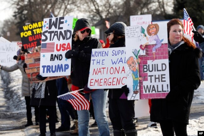 Supporters hold signs at a Women for Trump "Build the Wall" rally in Bloomfield Hills, Mich., Jan. 26, 2019.