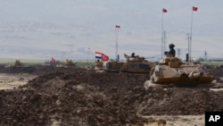 Turkish and Iraqi soldiers sit on Turkish tanks during the exercises in Silopi, near the Habur border gate with Iraq, southeastern Turkey, Sept. 26, 2017.