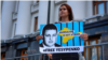 FILE - The wife of the arrested Vladyslav Yesypenko, Kateryna, with a poster in his support near the Office of the President of Ukraine in Kyiv, July 7, 2021.