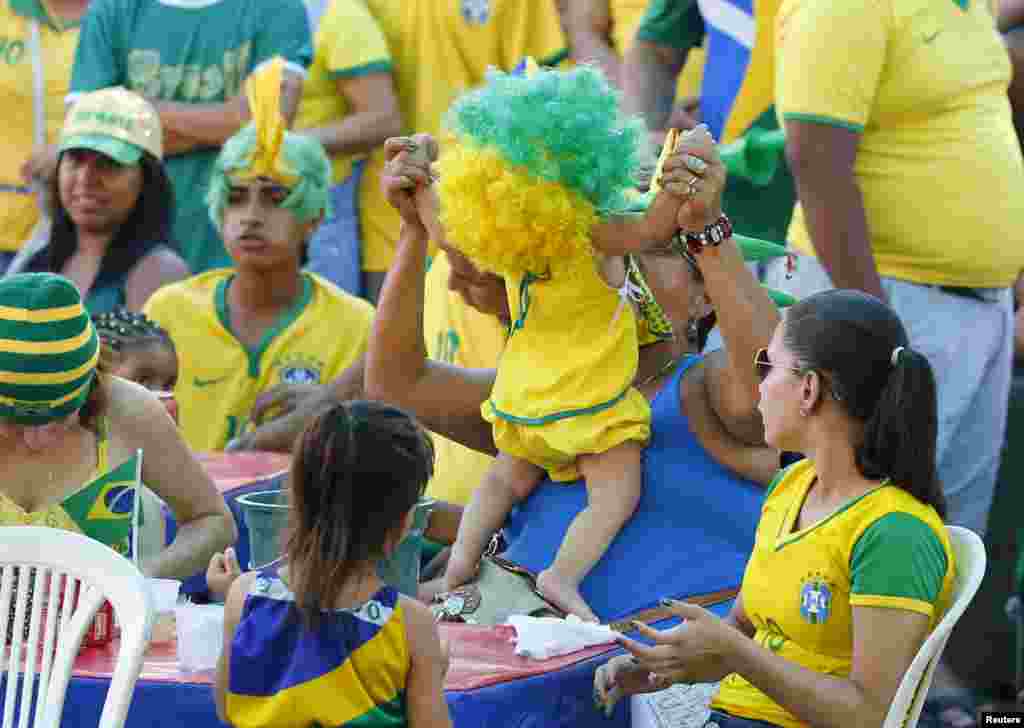 A baby wears a wig while playing among Brazilian soccer fans watching the match between Brazil and Mexico during the World Cup 2014, in Manaus, June 17, 2014.