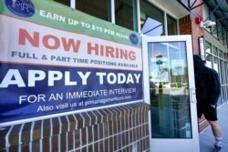 FILE - A man walks into a restaurant displaying a "Now Hiring" sign, March 4, 2021, in Salem, N.H. For some people, looking for a new job to replace one lost to the pandemic will be a stressful experience.