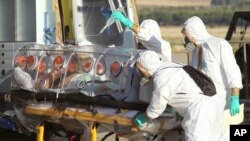 In this photo provided by the Spanish Defense Ministry, aid workers and doctors transfer Miguel Pajares, a Spanish priest who was infected with the Ebola virus while working in Liberia, from a plane to an ambulance as he leaves the Torrejon de Ardoz milit