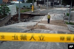 A security guard walks on an earthquake-buckled street in Kiyota, on the outskirts of Sapporo, Hokkaido, northern Japan, Sept. 7, 2018.