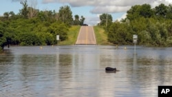 Un agente de la patrulla de caminos de Dakota del Sur observa un puente inundado tras días de fuertes lluvias en la zona, cerca de Lake Alvin, Dakota del Sur, el sábado 22 de junio de 2024.