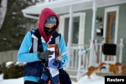 Mail carrier Tiffany Sufficool delivers the mail during subzero (fahrenheit) temperatures in Fargo, North Dakota, U.S., January 31, 2019. REUTERS/Dan Koeck