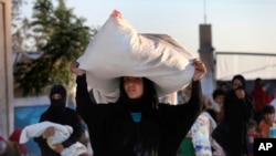 A Syrian woman who fled with her family the battle between U.S.-backed Syrian Democratic Forces (SDF) and the Islamic State militants from Raqqa city, carries her belongings upon her arrival at a refugee camp, in Ain Issa, July 24, 2017.